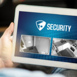 Man using home security system and application in tablet. Watching protection camera live footage inside a house or apartment.